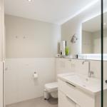 Badezimmer mit Waschbecken, Spiegel, Toilette und Heizkörper.