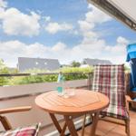 Balkon mit Tisch, Stühlen und Blick auf Häuser und Bäume.