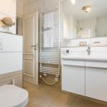 Badezimmer mit Waschbecken, Spiegel, Toilette und Handtuchheizung.
