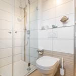 Badezimmer mit Dusche, WC und Waschmaschine. Blick in das Schlafzimmer.