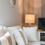 Ein Wohnbereich mit Sofa, Fernseher und Stehlampe.
