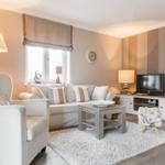 Wohnzimmer mit Sofa, Sessel, Couchtisch und Fernseher.