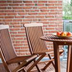 Terrasse mit Holztisch und zwei Stühlen. Auf dem Tisch steht eine Schale mit Äpfeln.