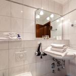 Badezimmer mit Spiegel, Handtuchhalter und Duschbereich.