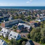 Aerial view of a coastal town with houses and greenery near the sea.