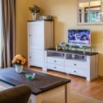 Wohnzimmer mit TV, Tisch, Stühlen und Fenster zum Balkon.