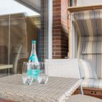 Terrace with table, chairs, and lounge. On the table is a water bottle and two glasses.