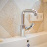 Sink with modern faucet and stone tile wall