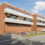 Red brick building with balconies and windows under blue sky.