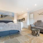 Bedroom with bed, sofa, and kitchen area. Wall art and shark decoration.