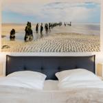 Bedroom with bed and wall art of beach and posts.