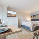 Bedroom with bed, table, and wall art. TV and cabinet are visible.