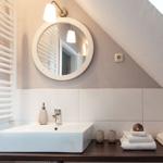 Dusche mit Waschbecken, Spiegel und Handtüchern unter Dachschrägen.