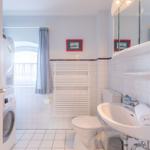 Badezimmer mit Waschmaschine, Toilette und Waschbecken