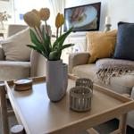 Wohnzimmer mit Couch, Tisch und Blumen.