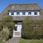 Haus mit Dachfenstern, weißer Tür und Hecke