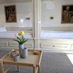 Zwei Betten mit weißen Laken, Tisch mit Tulpen und Wandbildern.