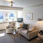 Wohnzimmer mit Sofa, Sessel und TV. Fenster mit Blick auf Dach. 