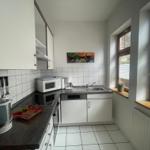 Küche mit hochwertigem Cerankochfeld, Backofen, Geschirrspüler, Kühl-Gefrierschrank, Mikrowelle, Kaffeemaschine, Wasserkocher und Toaster.