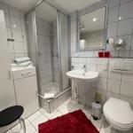 Bad mit Toilette, Dusche und Waschbecken mit beleuchtetem Spiegel.
