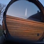 Private Wellnessmomente in unserer stilvollen Fasssauna mit Panoramafenster im Garten – inklusive verschiedener Duftaufgüsse.