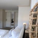 Schlafzimmer mit Bett, Nachttisch und geflochtenem Regal