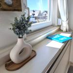 Fensterbank mit Vasenpflanze und Buch. Blick auf Straße und Häuser.