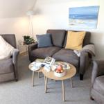 Ein Wohnzimmer mit Sofa, zwei Sesseln und einem runden Tisch.
