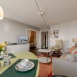 Wohnzimmer mit Sofa, Esstisch und Fernseher. Helle Wandfarbe und moderne Einrichtung.