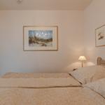 Schlafzimmer mit Bett, Wandbildern und Nachttischlampe.