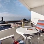 Balkon mit Tisch, Stühlen und Blick auf das Meer.