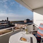 Balkon mit Tisch, Stuhl und Seeblick auf Gebäude und Strand.