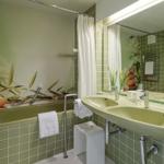 Bad mit Dusche, Waschbecken und Spiegel. Wandbild mit Steinen und Bambus.