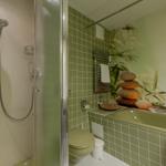 Bad mit Dusche, Toilette und Badewanne mit Steinpyramide und Kerze.