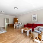 Wohnung mit Essbereich, rotem Sofa und Kamin. Holzboden und moderne Einrichtung.