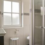 Badezimmer mit Dusche, Toilette und Fenster mit Milchglas