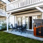 Terrasse mit Tisch und Stühlen, angrenzender Eingang und Gartenbereich.