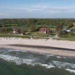 Strand mit Wellen, Strandkörben und Häusern im Hintergrund