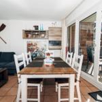 Essbereich mit Tisch und Stühlen, Sofa mit Kissen, Terrasse und Glaswand.