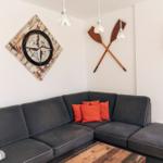 Ein Wohnzimmer mit grauem Sofa, orangefarbenen Kissen und einem Holztisch.