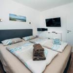 Schlafzimmer mit Doppelbett, Fernseher und Badetücher.