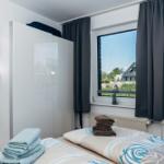 Schlafzimmer mit Bett, Gardinen und Blick auf Außenbereich.
