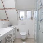 Badezimmer mit Dusche, Waschbecken und Toilette unter Dachschrägen.