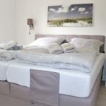 Doppelbett mit Bettwäsche, Wandbild und Nachttisch