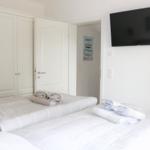 Schlafzimmer mit Bett, Kleiderschrank und Wandfernseher.