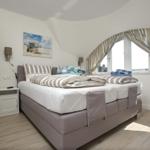 Schlafzimmer mit Doppelbett, Fenster und Wandbild.