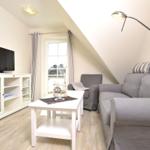 Wohnzimmer mit Sofa, Sessel, TV und Fenster