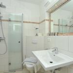 Badezimmer mit Dusche, Waschbecken und Spiegel