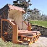 Strandkorb mit Sitzbank und Weinflasche auf Steinmauer