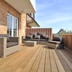 Terrasse mit Sitzgruppe, Holzdielen und Backsteinwand. Blick auf den Himmel.
